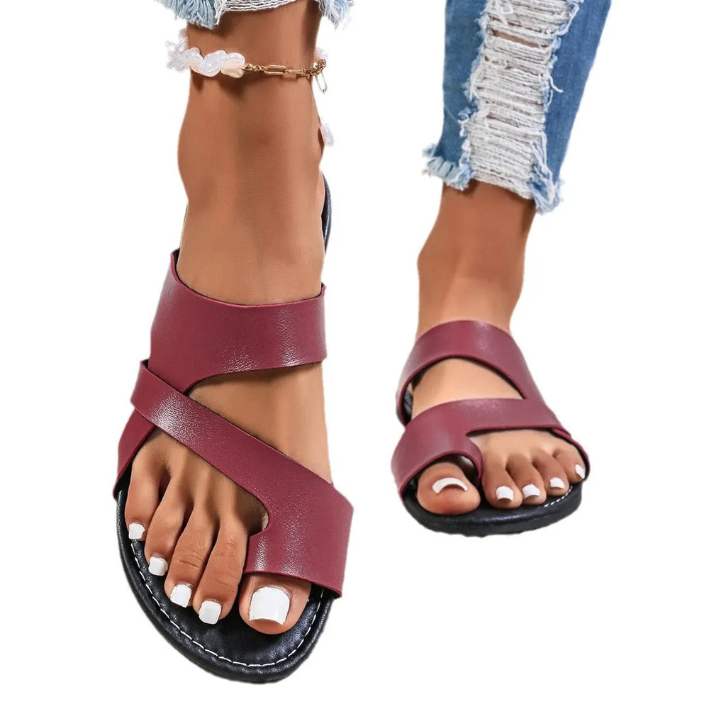 Men's casual beach slippers in black with hollow-out design and leather lining, shown on a sandy beach.