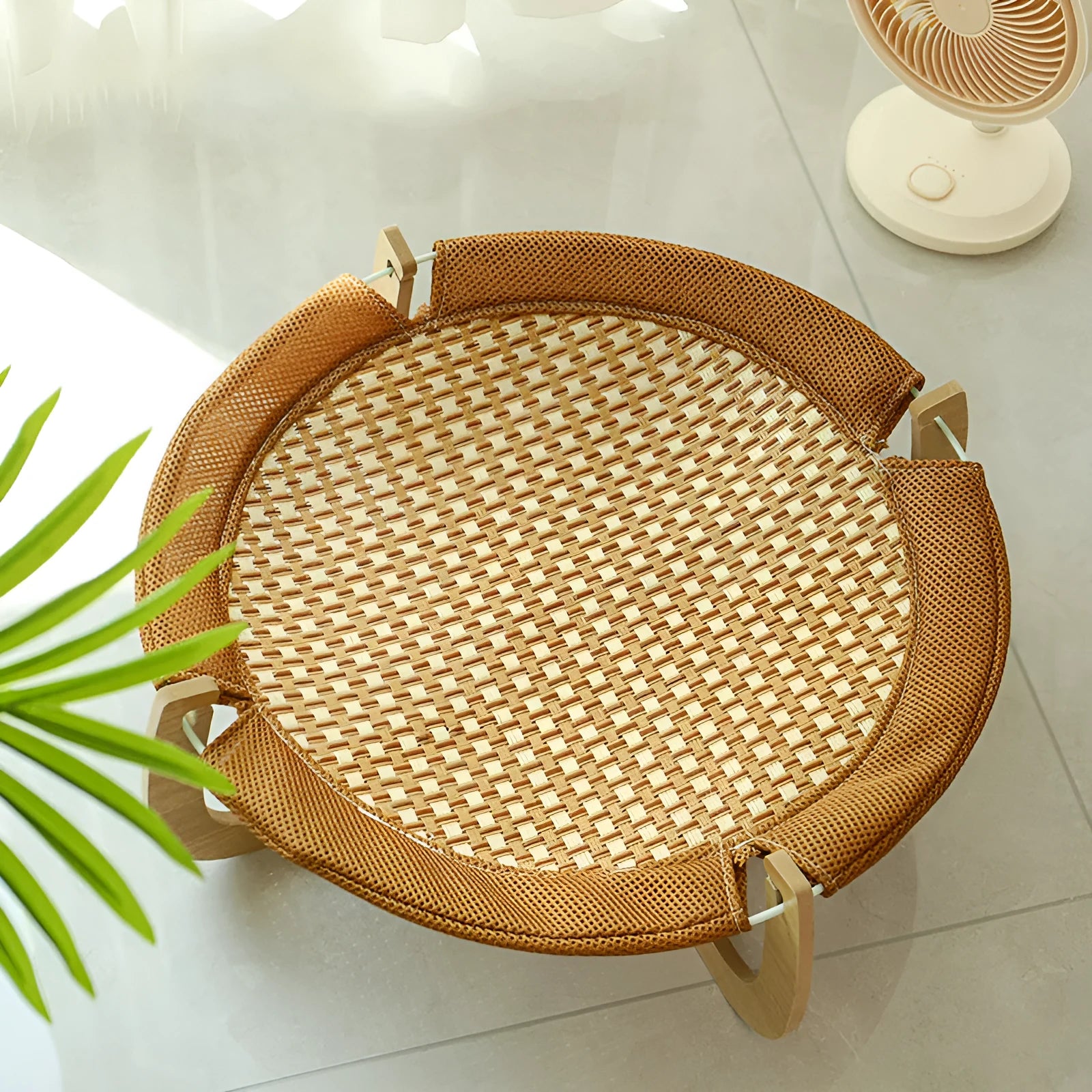 Brown square woven rattan raised hammock bed for cats and dogs on a wooden floor.