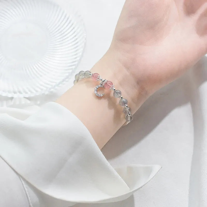 Handmade adjustable moonstone bracelet with crescent moon charm and crystal bead on a white background.