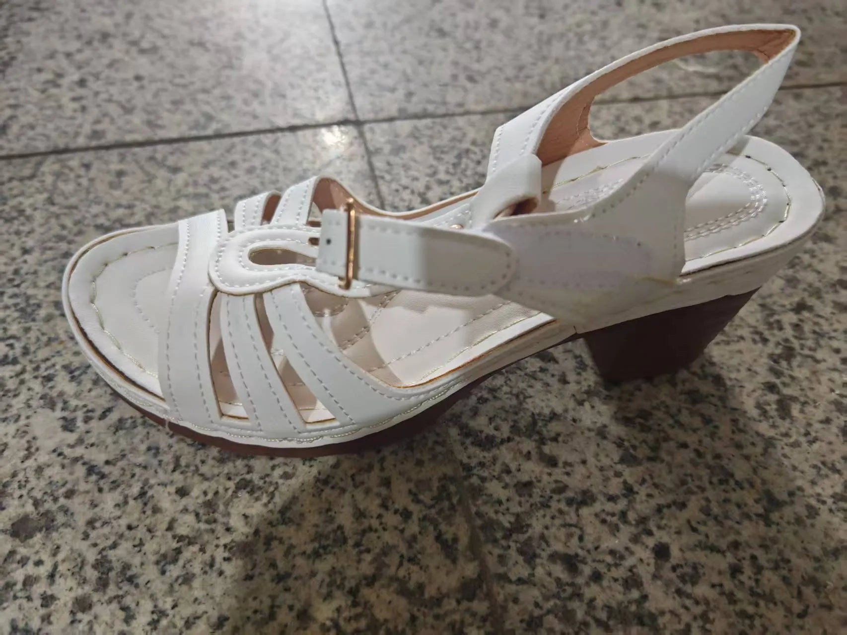 Women's black peep toe wedge platform sandals with a buckle fastening on a wooden surface.
