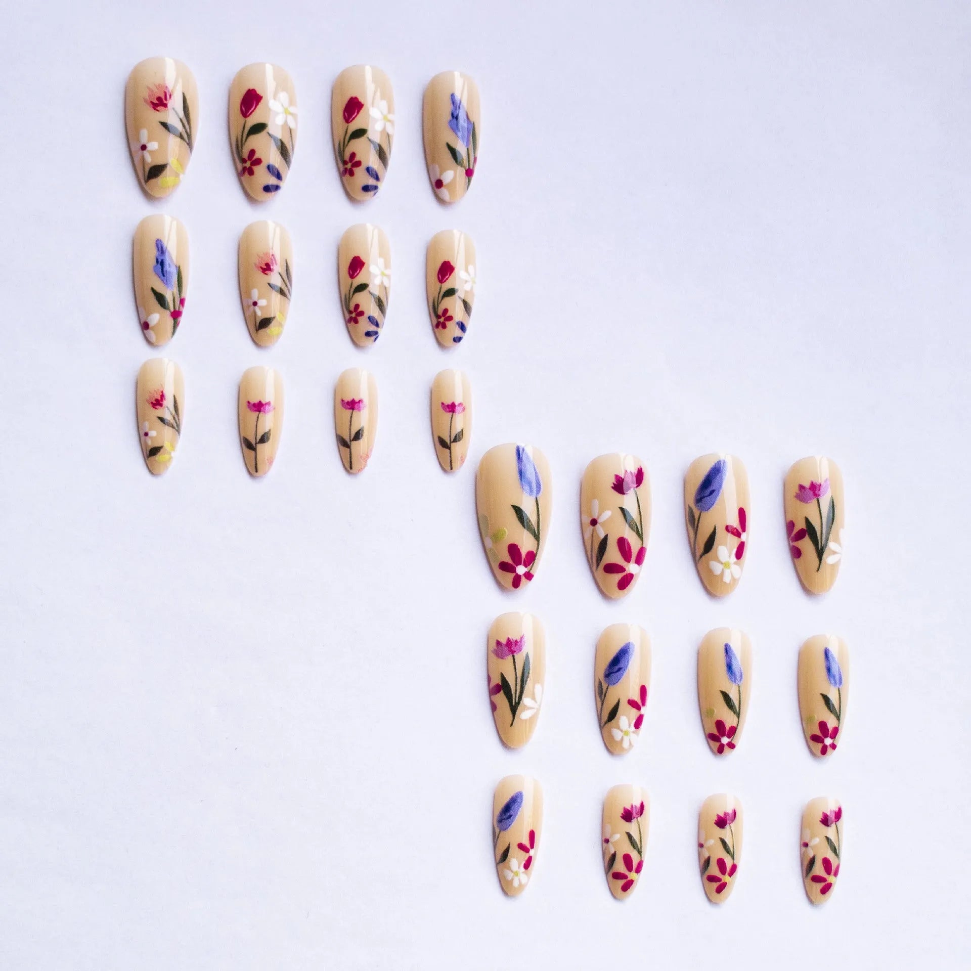 Almond-shaped false nails with detailed 3D pink rose and tulip floral designs on a solid colour base.