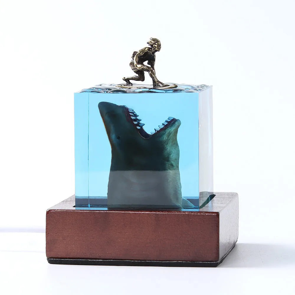 Close-up of a crystal resin shark surfer night light ornament on a dark surface.