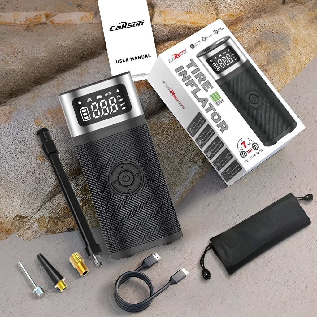 Black portable wireless air pump with USB charging cable, inflation tube, and a set of nozzles on a grey background.