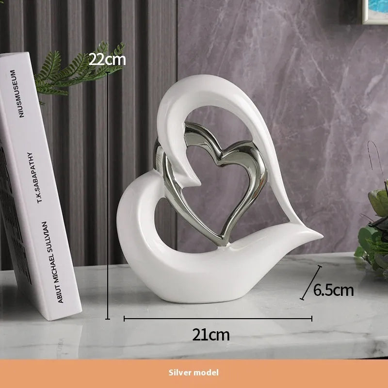Modern white porcelain heart ornament in a metallic finish, showing its geometric shape on a table.