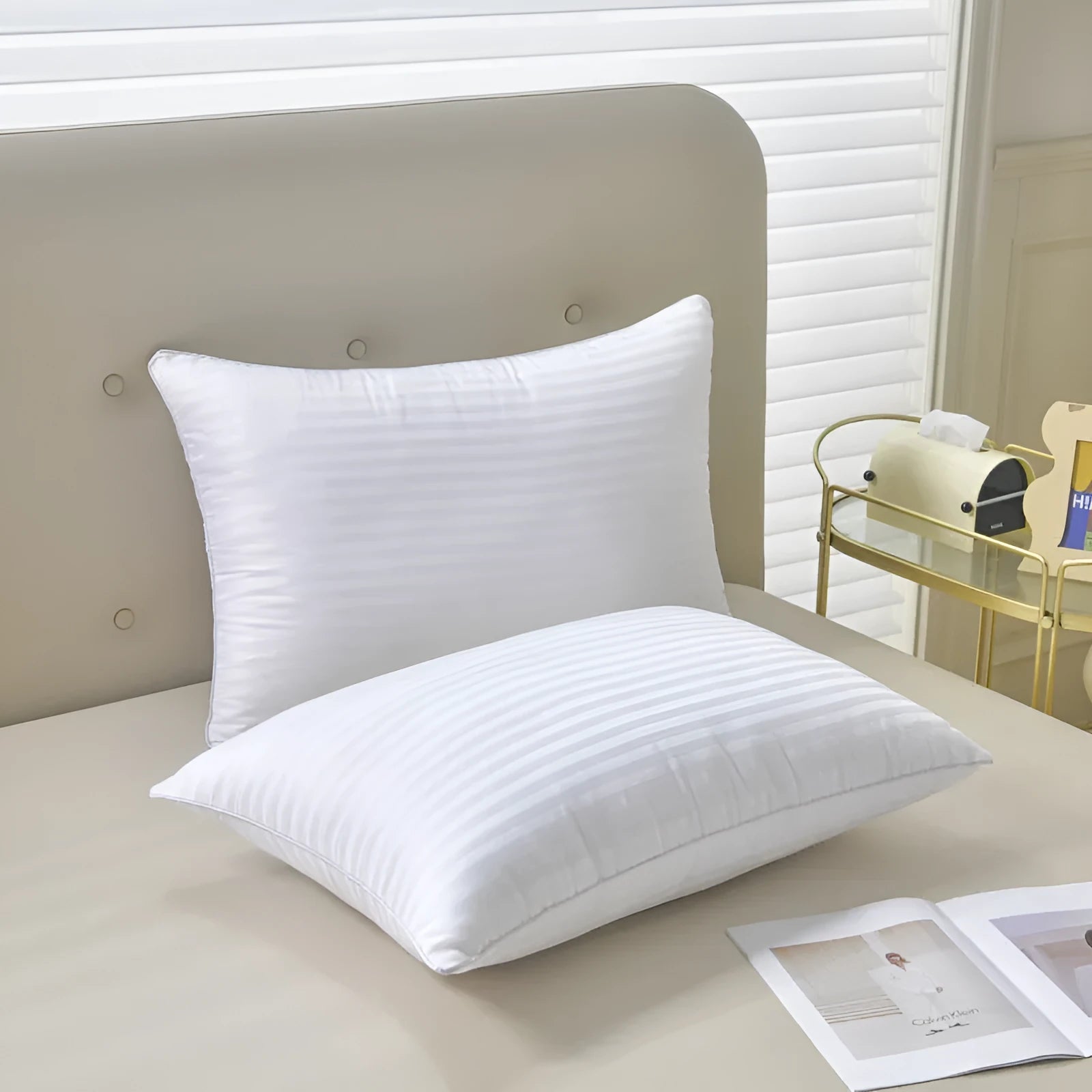 White cotton satin stripe pillow with feather and cotton filler on a bed.