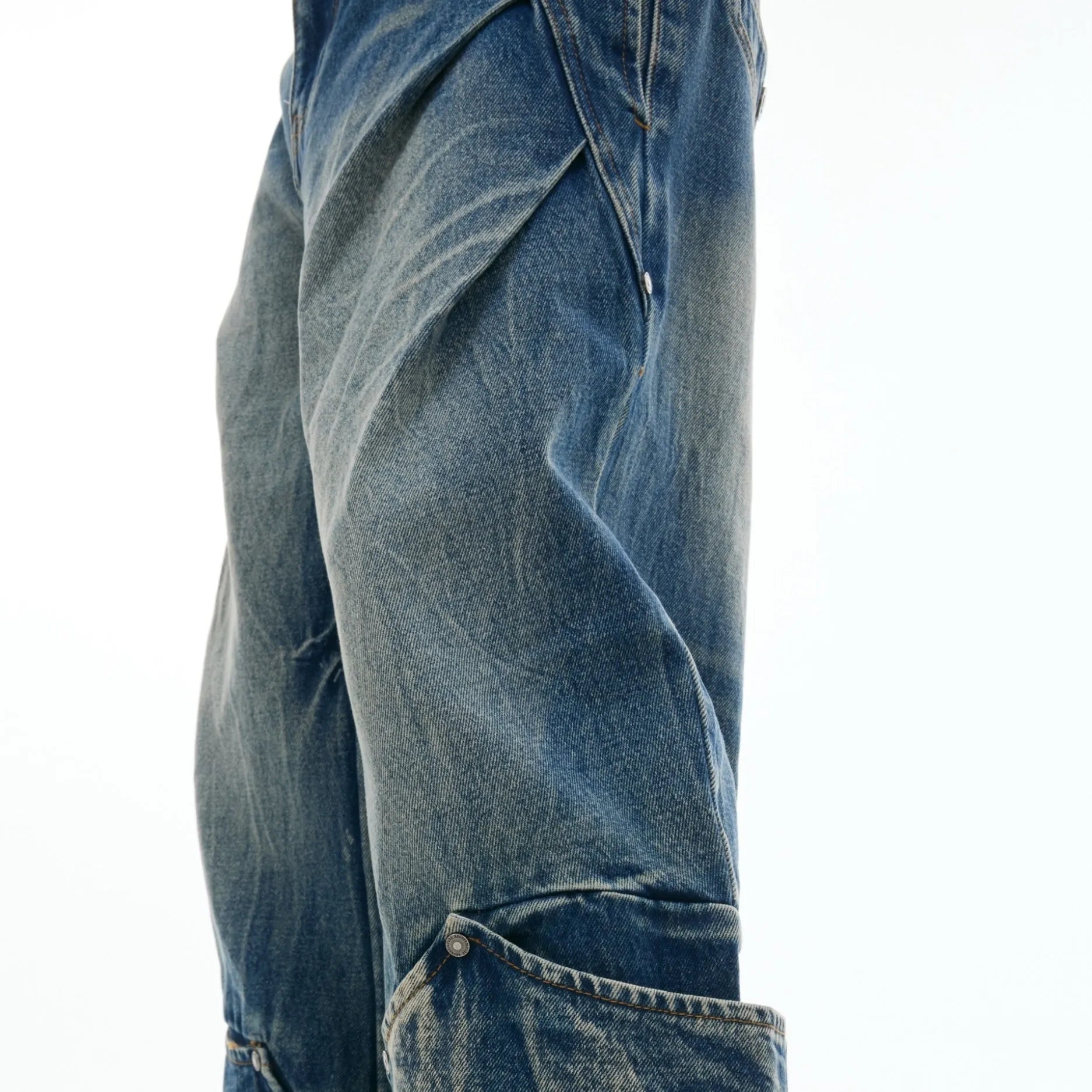 Man wearing verdant blue retro washed burst pattern loose fit jeans with a curved knife design.
