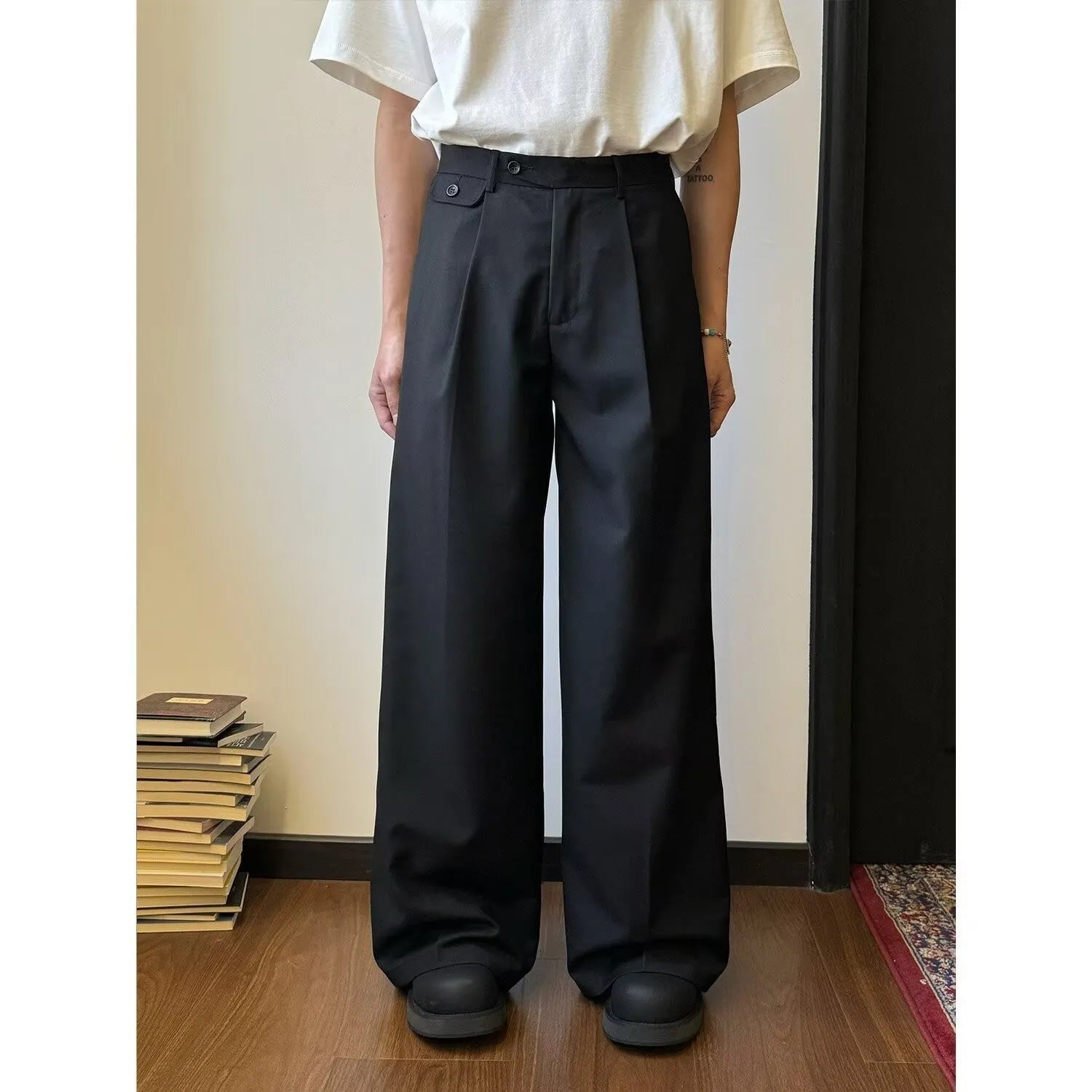 Men's straight-leg casual trousers in black with wide-leg draping silhouette on hanger