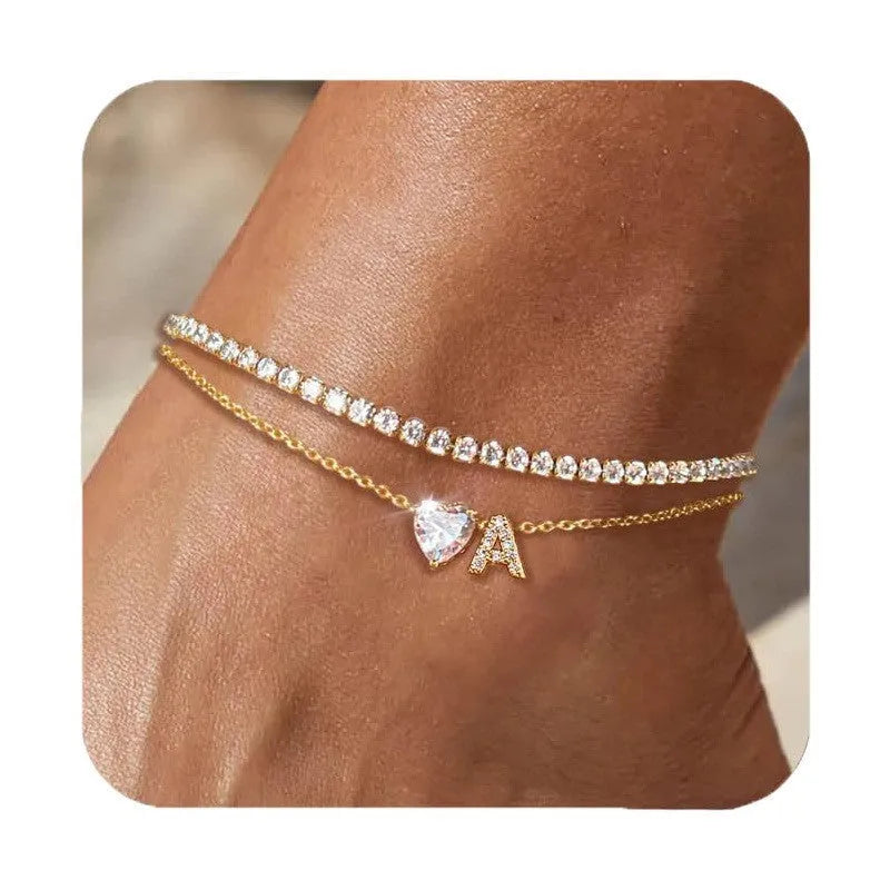 Layered copper anklet with zircon inlaid letter charm, bead zircon style, on a light background.