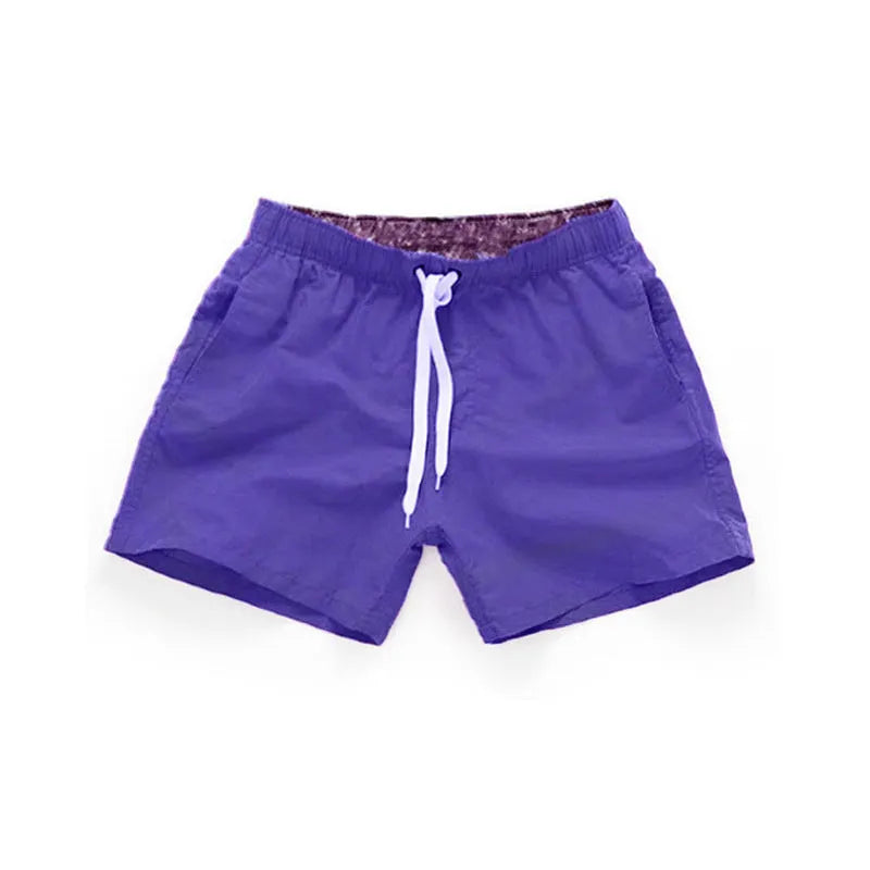 Men's black surf shorts made from polyester fabric with a straight leg opening, shown on a size chart.