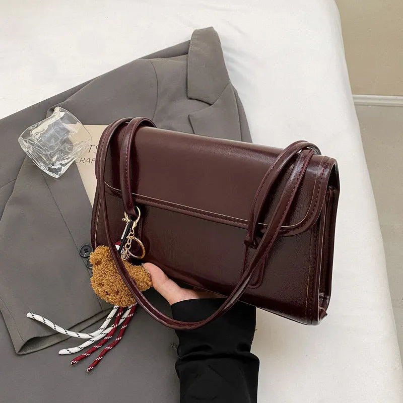 Brown women's Maillard-style PU leather shoulder bag with a double strap and a removable pendant accessory.