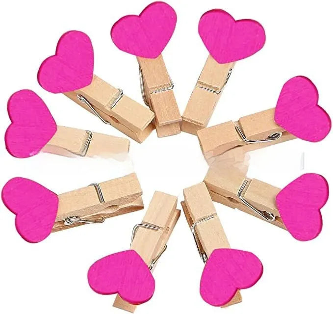 Set of five solid wood heart-shaped clips in different colours on wooden surface