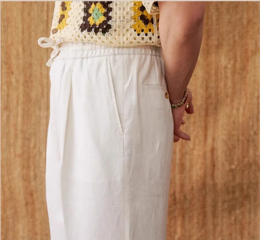 A pair of loose-fit, high-waisted linen trousers in a neutral colour with an elasticated waistband and straight legs.