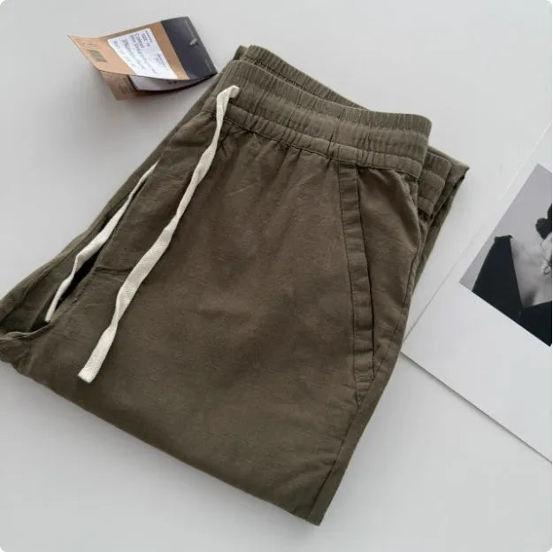 Man wearing beige loose straight leg casual trousers with a drawstring waistband.