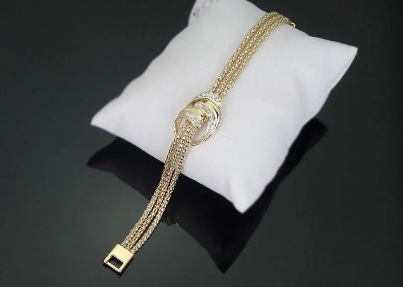 Gold alloy jewelry set with necklace, bracelet, earrings, and ring on a neutral background