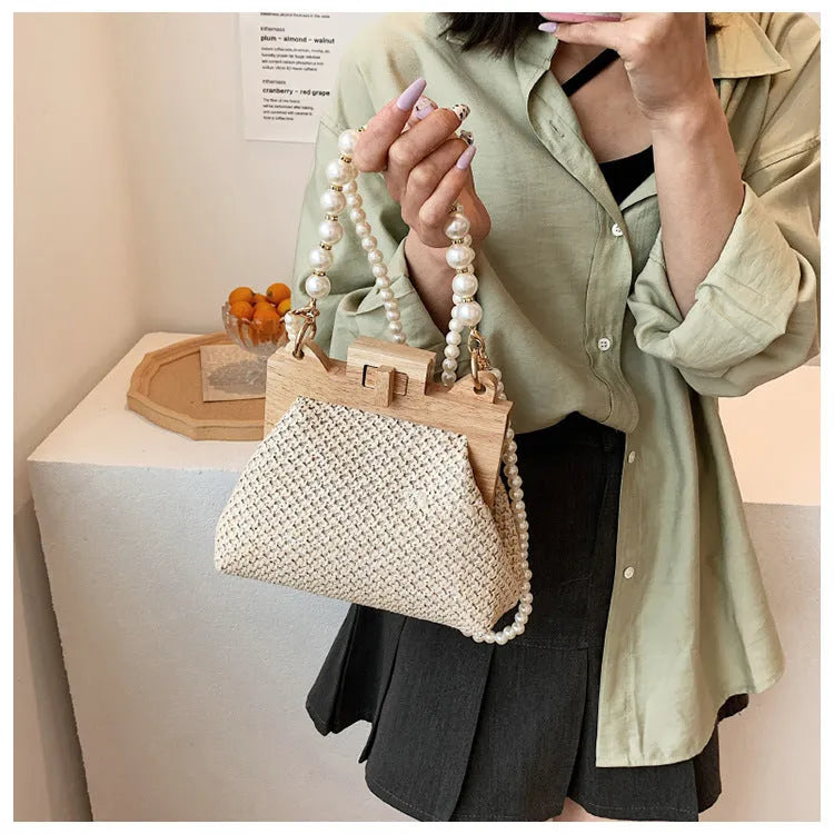 Women's woven straw shoulder bag with pearl chain strap in horizontal square shape showing sandwich pocket detail.