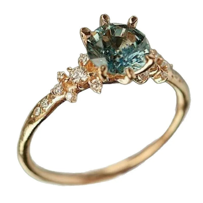 Gold plated geometric ring with claw inlaid zircon stones on a chamfered square pattern band.