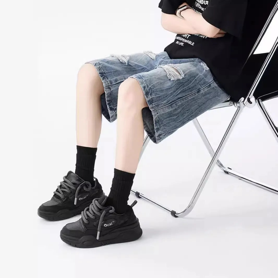 Man wearing loose blue ripped denim shorts with a vintage wash and distressed details.