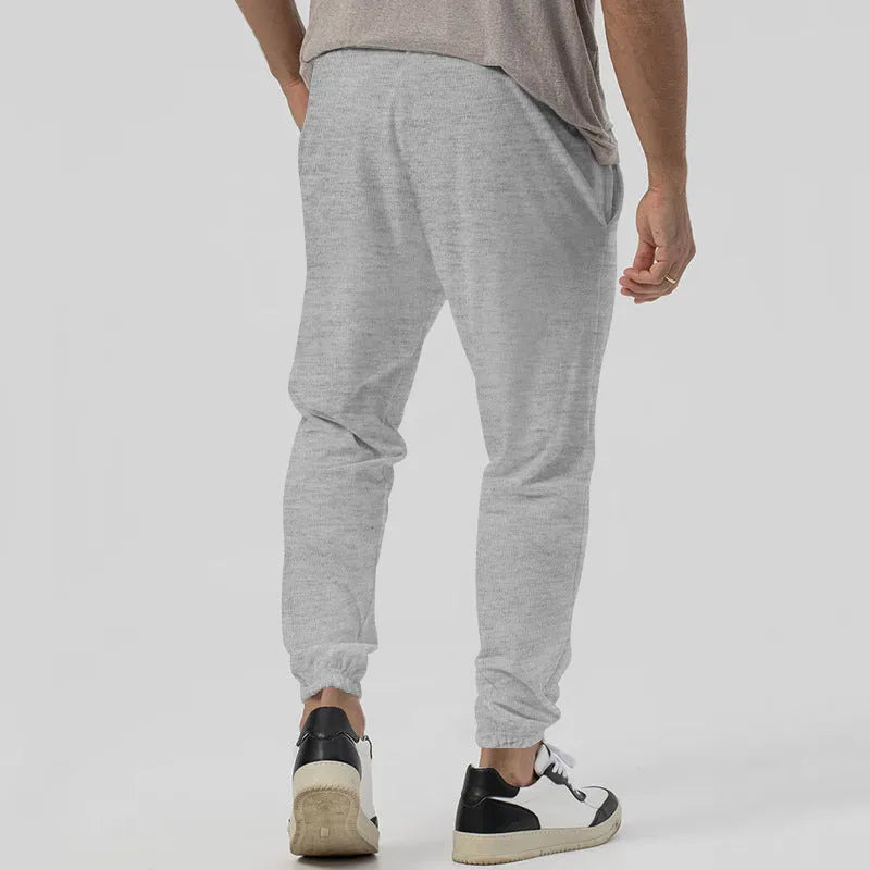 Men's loose tapered casual track sweatpants in cotton blend fabric showing straight-leg design