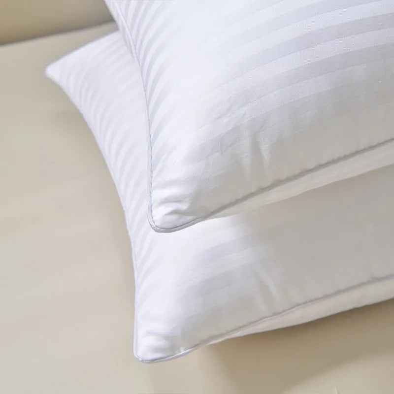 White cotton satin stripe pillow with feather and cotton filler on a bed.
