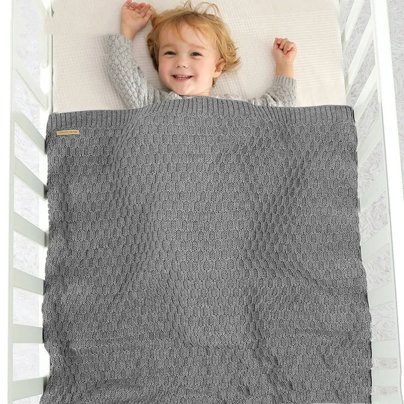 Solid colour infant blanket with textured lines, shown in a choice of colours including pink and beige.