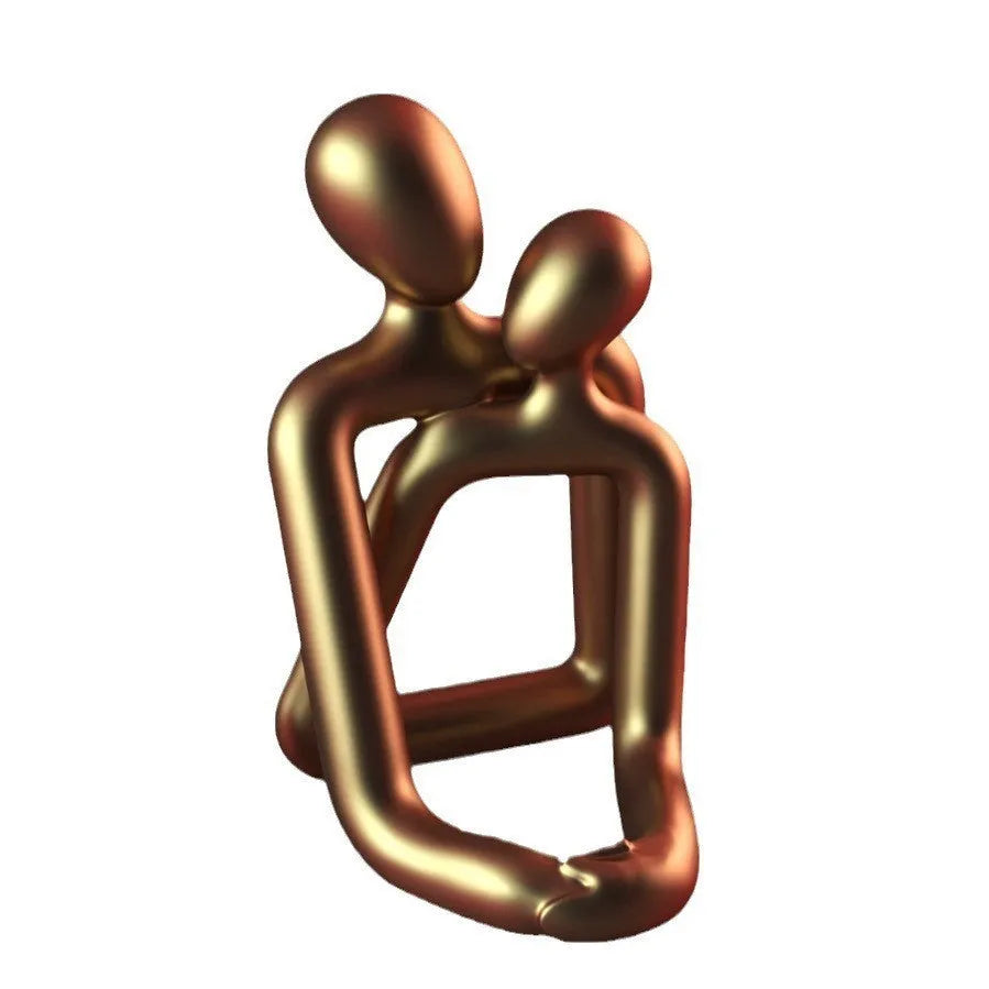 Modern style resin statue of a couple in milky white or gold colour on a wooden surface.